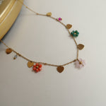 Load image into Gallery viewer, Necklace with floral charms on a light background