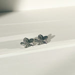 Load image into Gallery viewer, Silver flower-shaped earrings on a white surface
