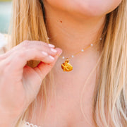 Close-up of a person wearing a delicate necklace with a small pendant.