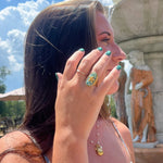 Load image into Gallery viewer, Woman with colorful rings and bracelets near a fountain
