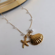 Gold necklace with shell and starfish charms on a light background