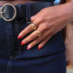 Load image into Gallery viewer, Close-up of a person wearing blue jeans with a black belt and gold rings on a blurred background
