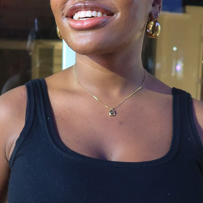 Woman wearing a black crop top and brown jacket indoors