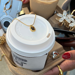 Load image into Gallery viewer, White coffee cup with a gold necklace on top, held by a person with red nail polish.
