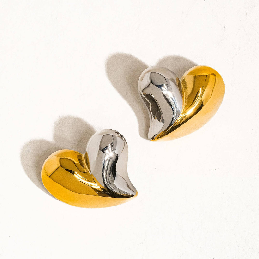 Pair of gold and silver heart-shaped earrings on a white background