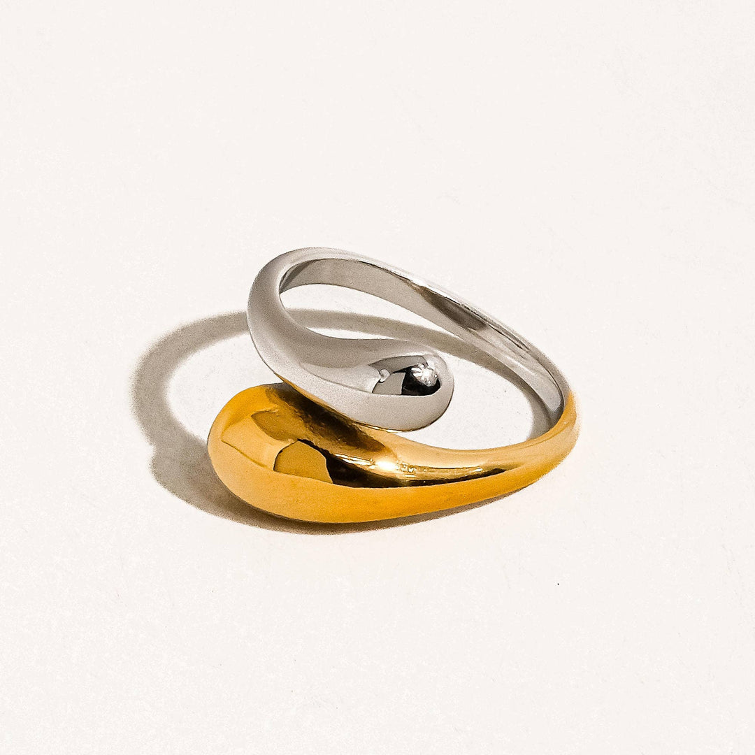 Two interlocking rings, one gold and one silver, on a light gray background.